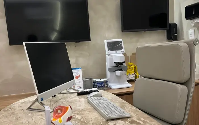 Consultório da Clínica de Olhos Dornelas, com modelo anatômico do olho sobre a mesa e tonômetro ao fundo.