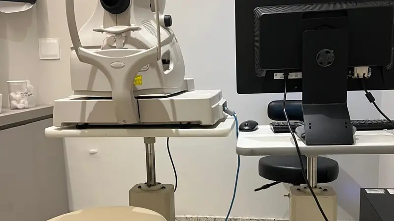 Retinógrafo da clínica, aparelho que fotografa o fundo do olho, ao lado do computador que registra o exame.