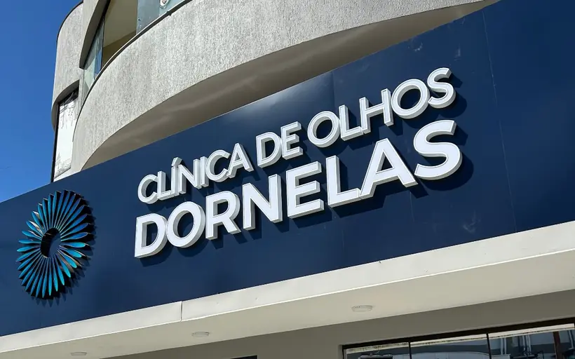 Fachada da Clínica de Olhos Dornelas vista da rua, com o letreiro azul sobre a entrada de vidro.