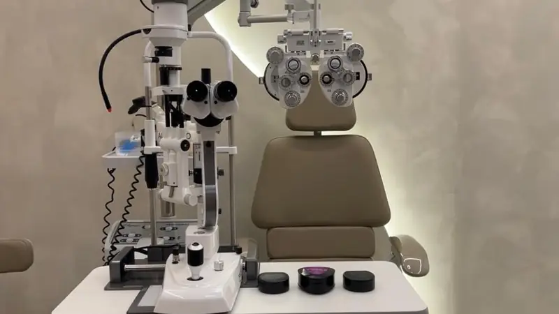 Sala de exame da clínica com poltrona, refrator e lâmpada de fenda prontos para o atendimento.
